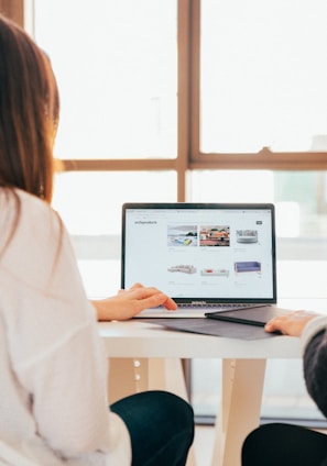 two women talking while looking at laptop computer