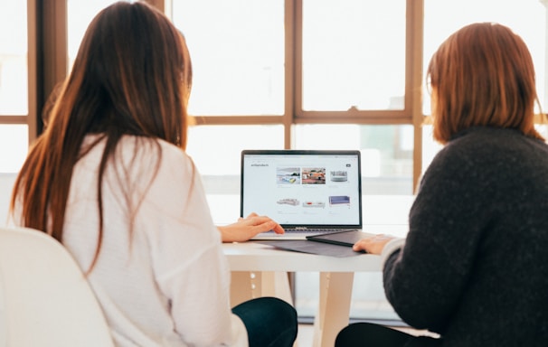 two women talking while looking at laptop computer