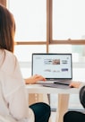 two women talking while looking at laptop computer