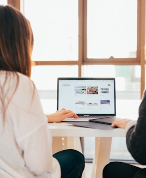 two women talking while looking at laptop computer