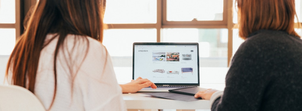 two women talking while looking at laptop computer