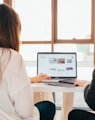 two women talking while looking at laptop computer