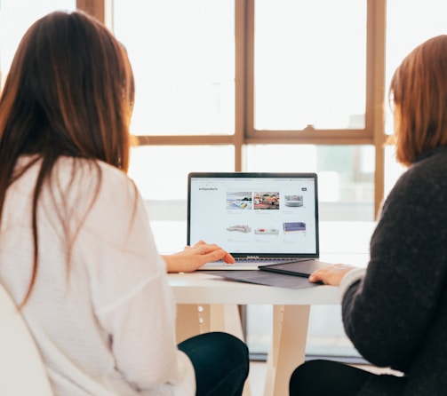 two women talking while looking at laptop computer