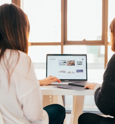 two women talking while looking at laptop computer