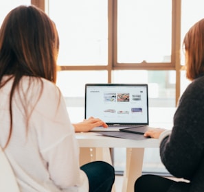 two women talking while looking at laptop computer