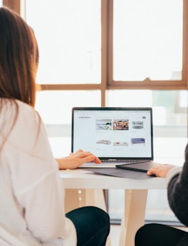 two women talking while looking at laptop computer