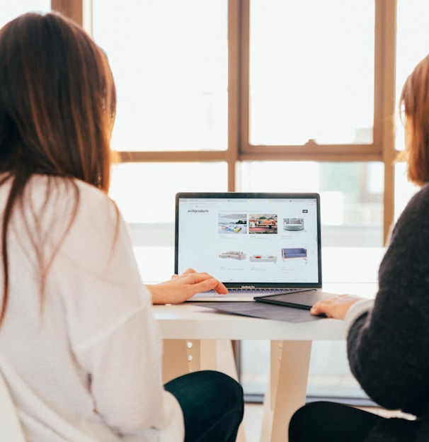 two women talking while looking at laptop computer