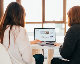 two women talking while looking at laptop computer