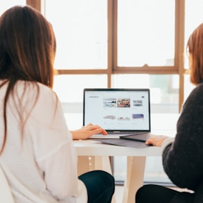 two women talking while looking at laptop computer