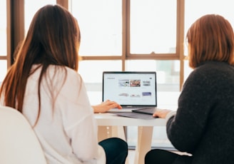 two women talking while looking at laptop computer