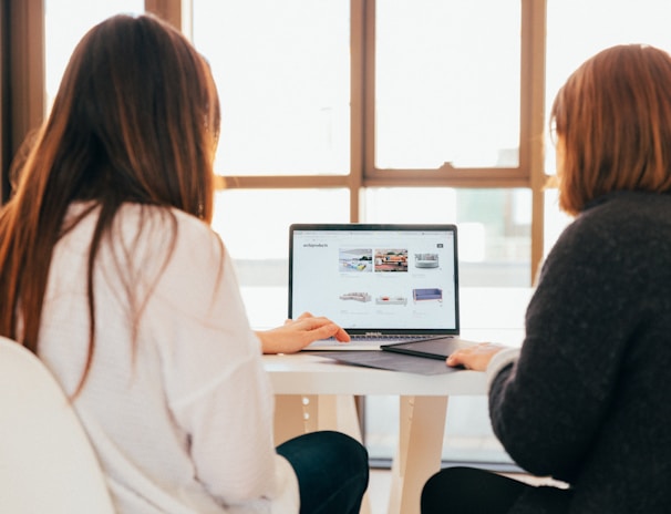 two women talking while looking at laptop computer