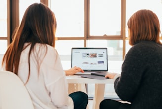 two women talking while looking at laptop computer