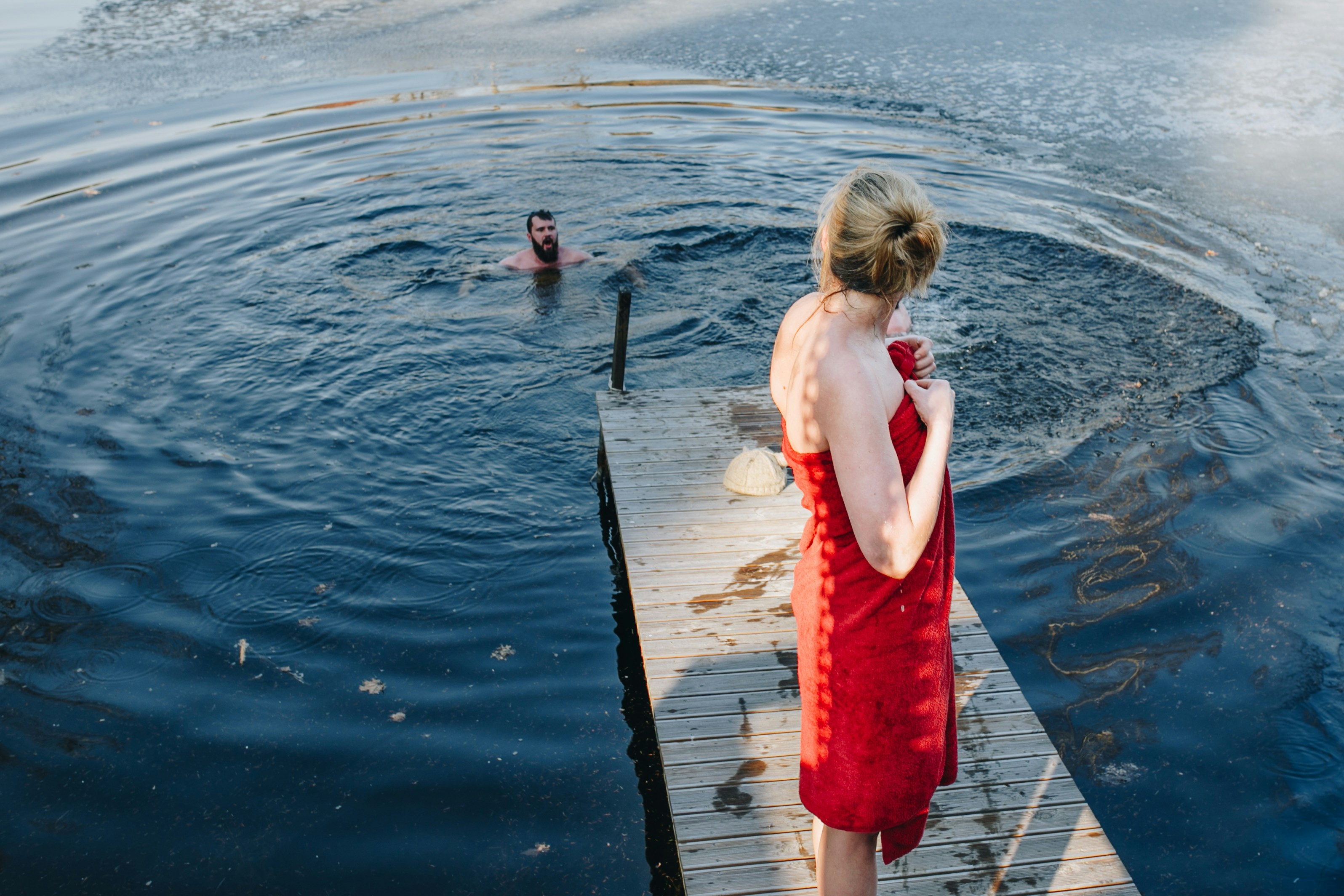 woman on jetty while man swims in water