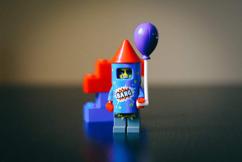 Juguete petardo de plástico LEGO verde azulado, rojo y morado en fotografía enfocada