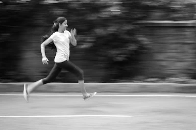 Close-up shot of a woman in high-compression leggings and a supportive top, mid-run on a city street.
