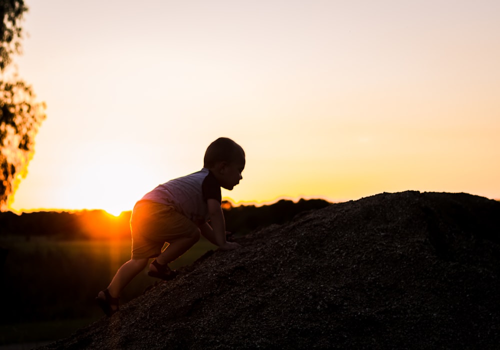 silhouette photography of child climbing on rock