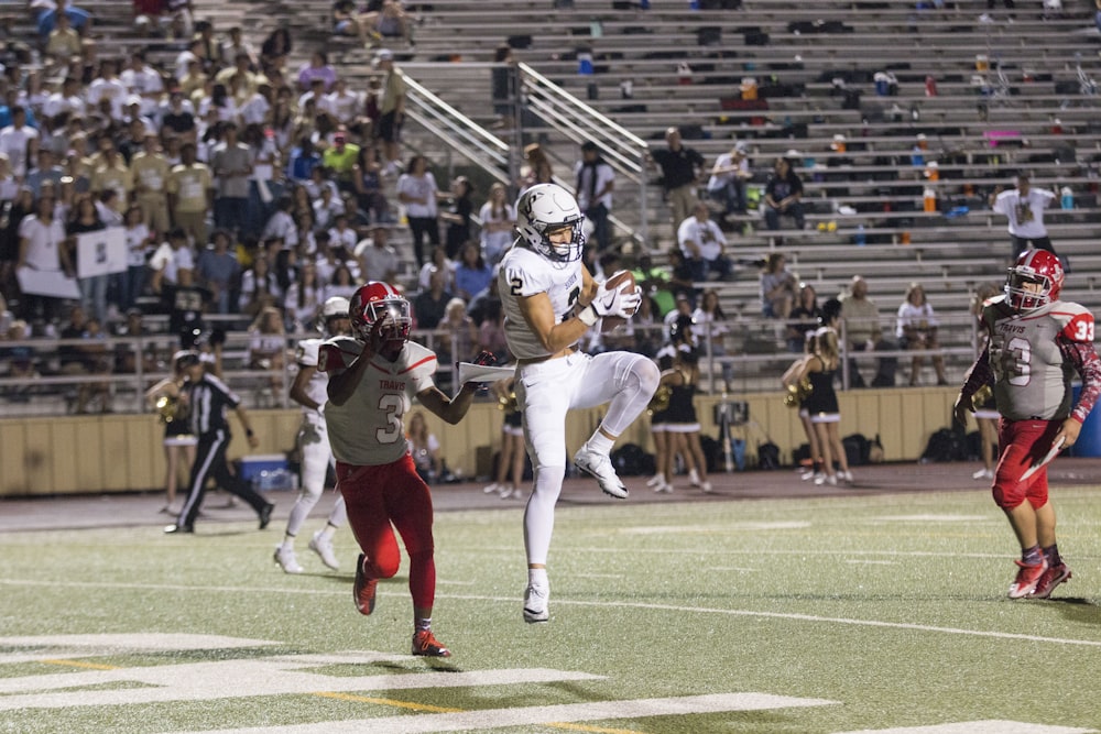 man catching brown football on stadium