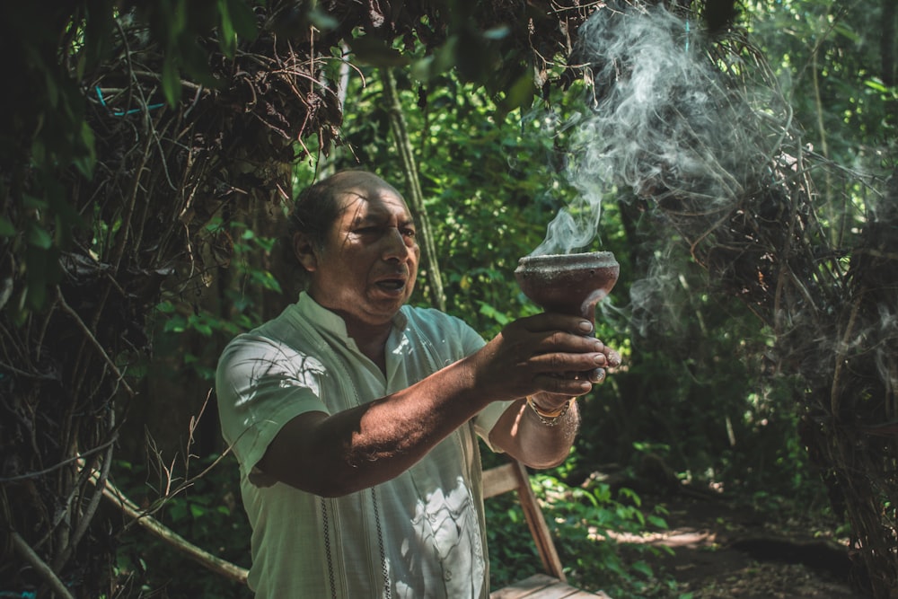 man holding brown pot with smoke
