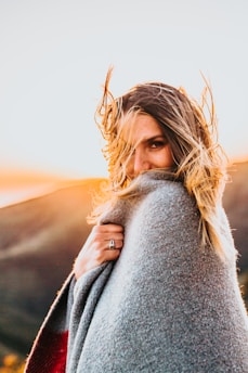 selective focus photography of woman covering herself with gray comforter