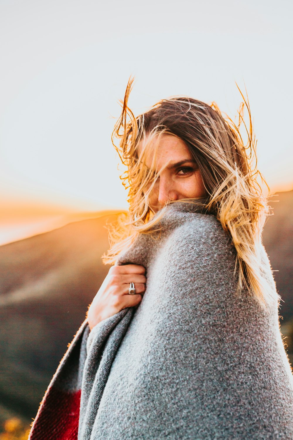 selective focus photography of woman covering herself with gray comforter