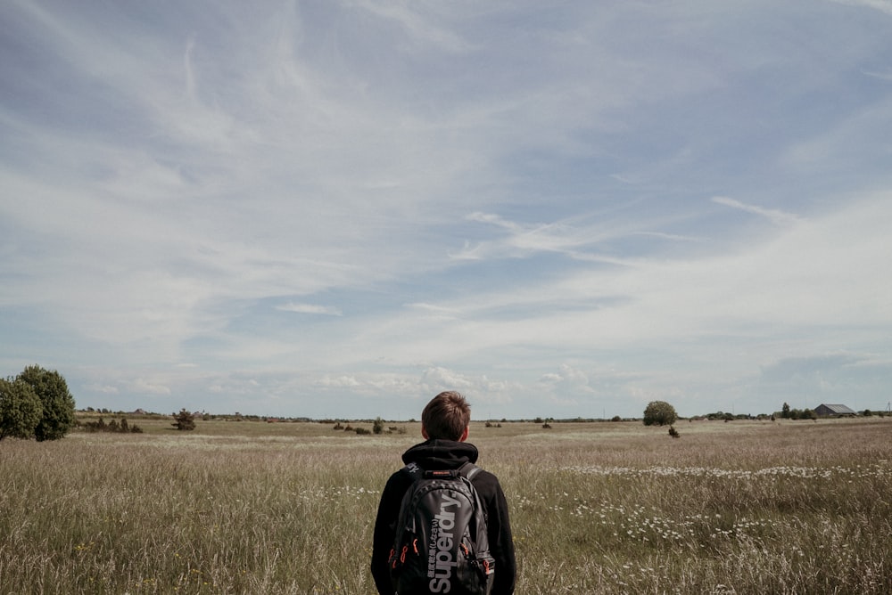 man standing on brown grass field under cloudy sky