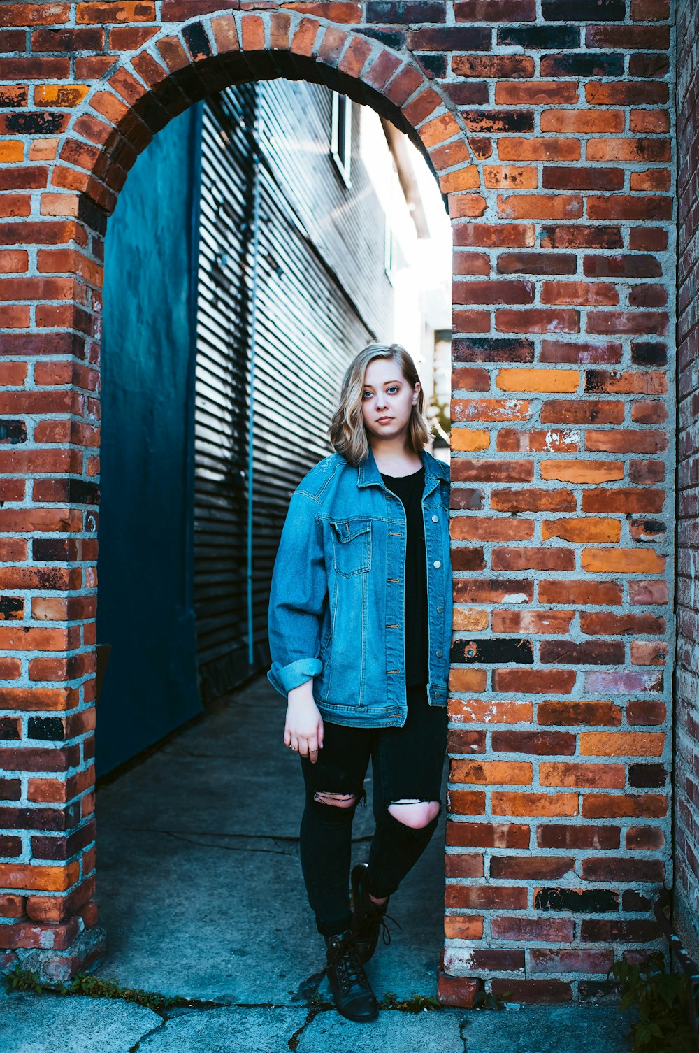 woman leaning on brown brick wall