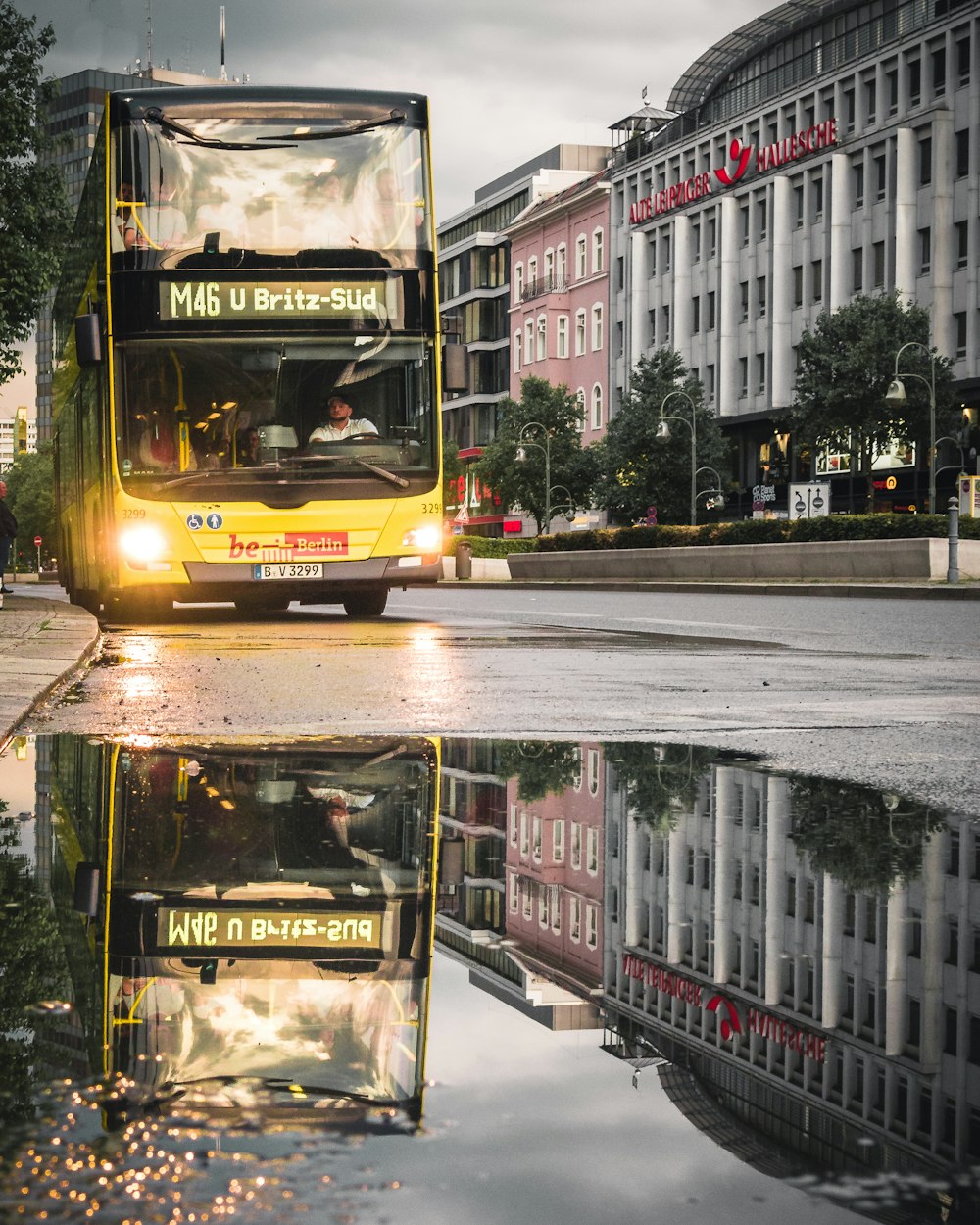 yellow bus reflecting on water near building