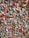 An intricate wall filled with thousands of pieces of colorful chewing gum arranged closely together, creating a textured and vibrant mosaic. Strings of gum add a dynamic, chaotic element to the surface.