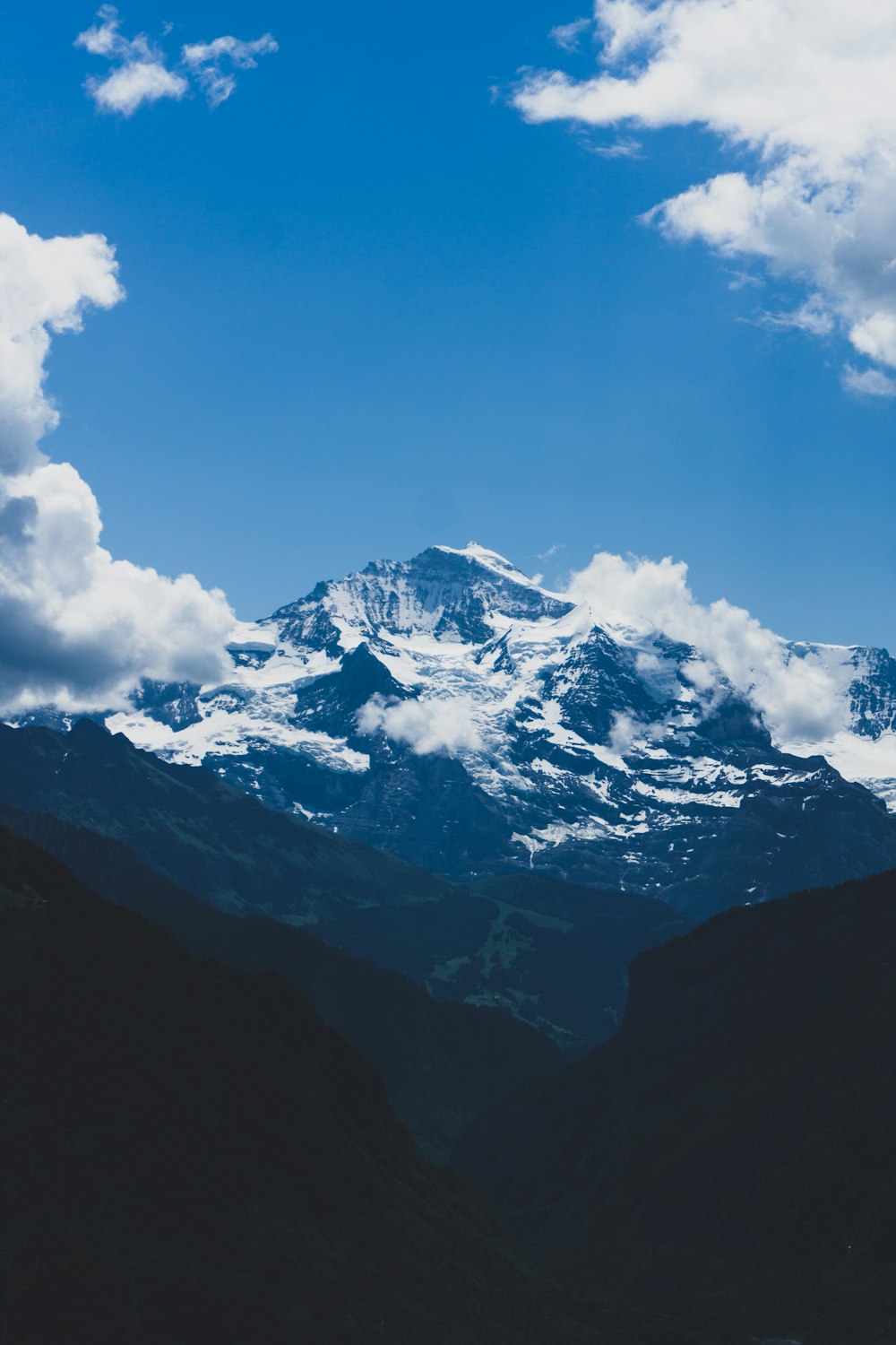 snow-covered mountain under white clouds during daytime