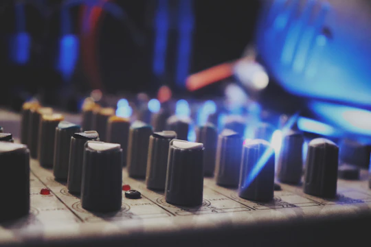 Close-up of a mixing console with glowing knobs and waveforms on a screen, capturing the essence of sound crafting.