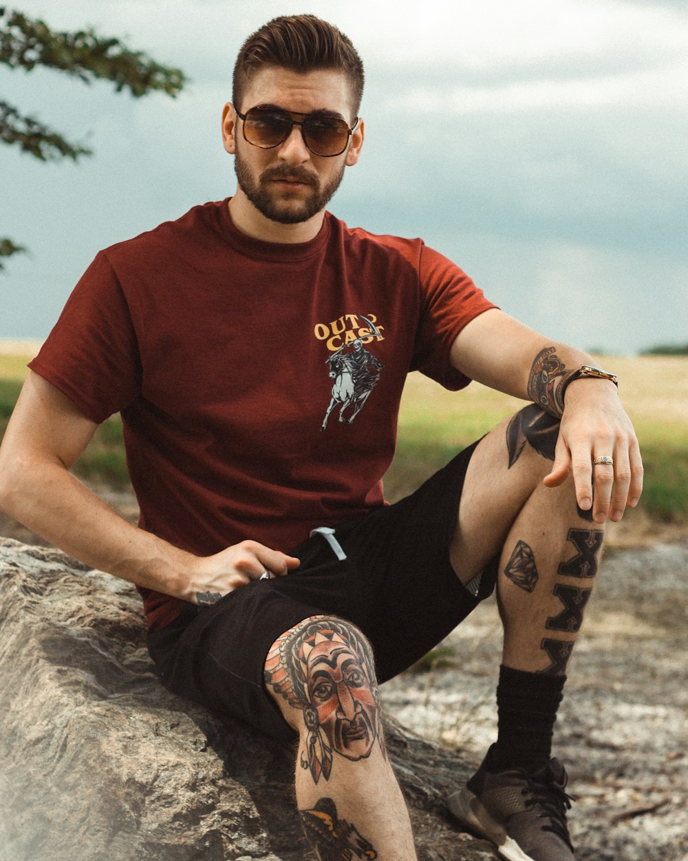 man sits on stone near grass field during daytime