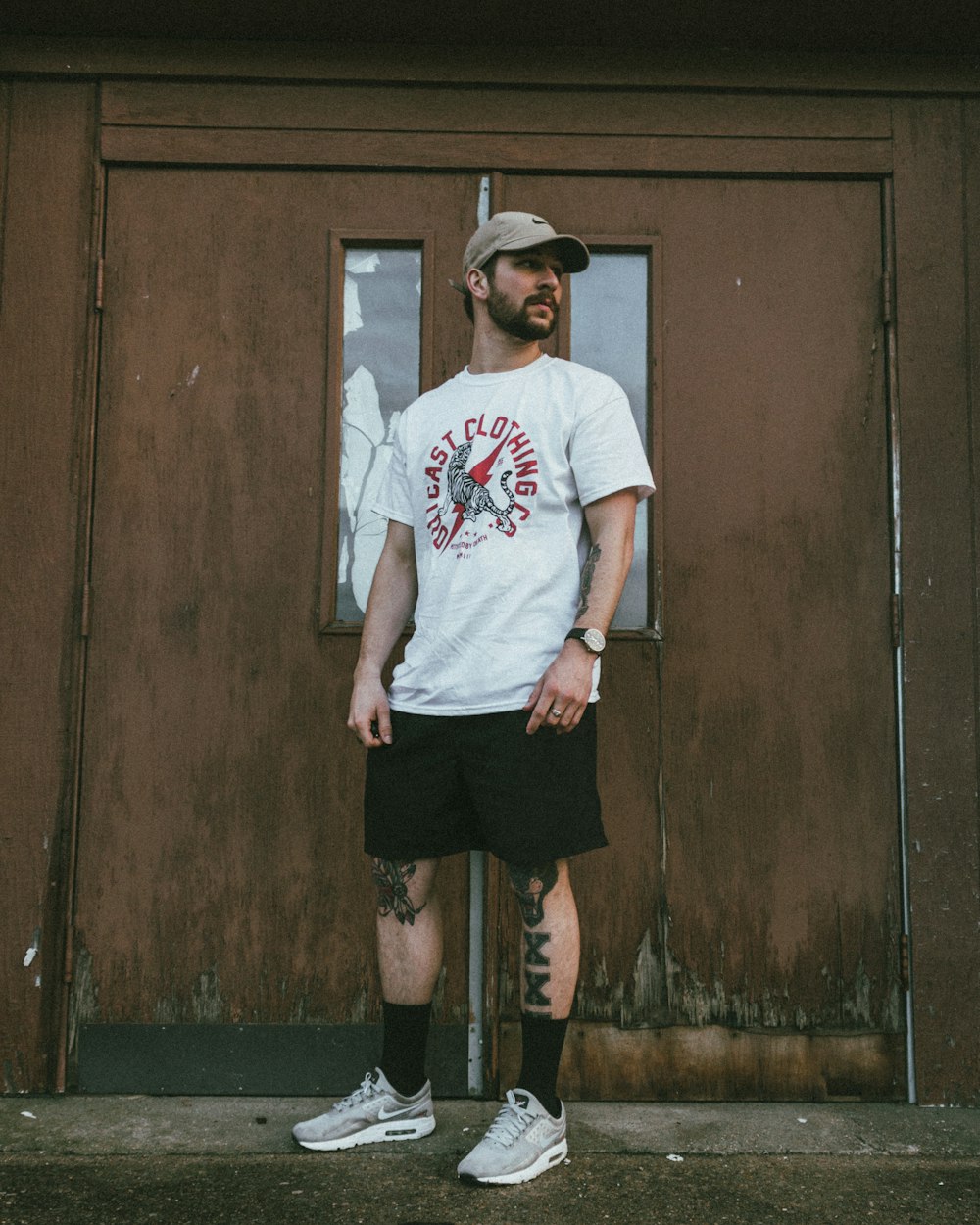 a man with tattoos standing in front of a door