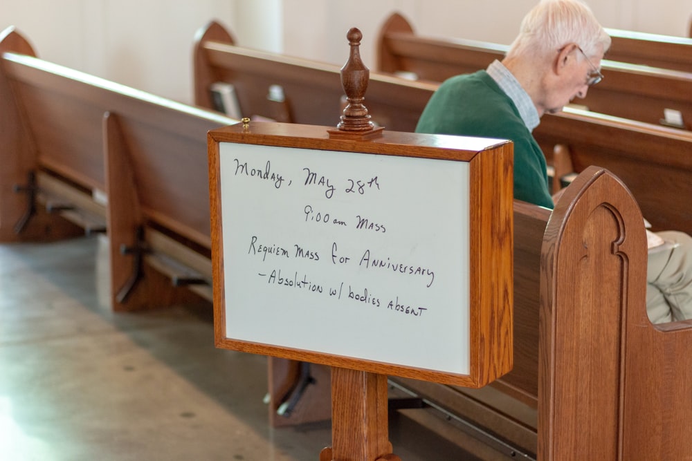 man sitting on brown wooden church pew