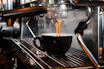 Close-up of a stainless steel coffee maker brewing a fresh cup on a clean countertop.
