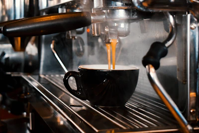 Close-up of a stainless steel coffee maker brewing a fresh cup on a clean countertop.