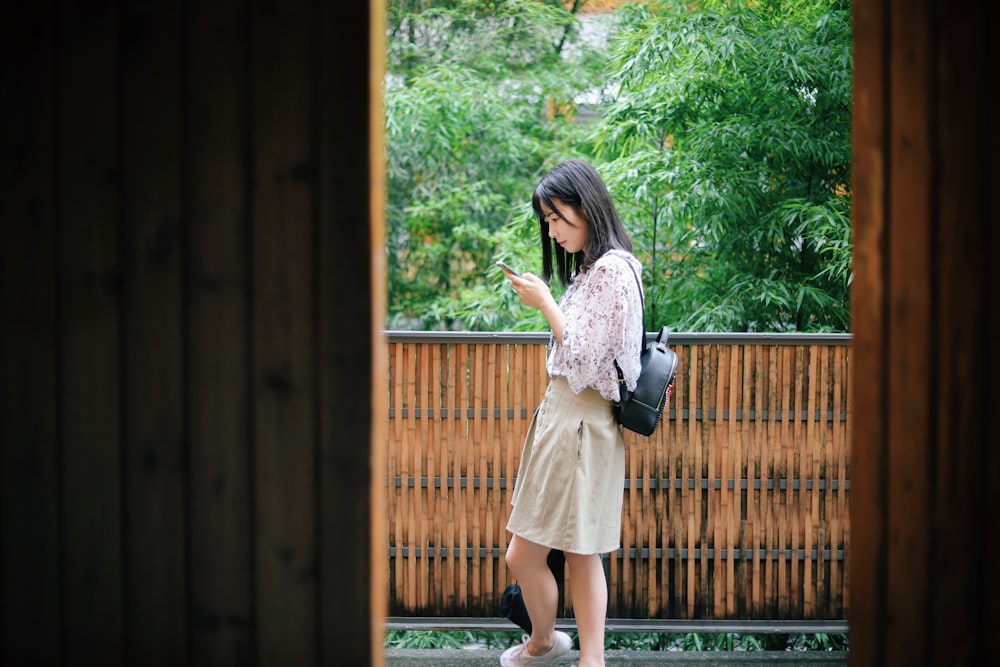 femme debout près du balcon en bois brun et noir sur des arbres à feuilles vertes