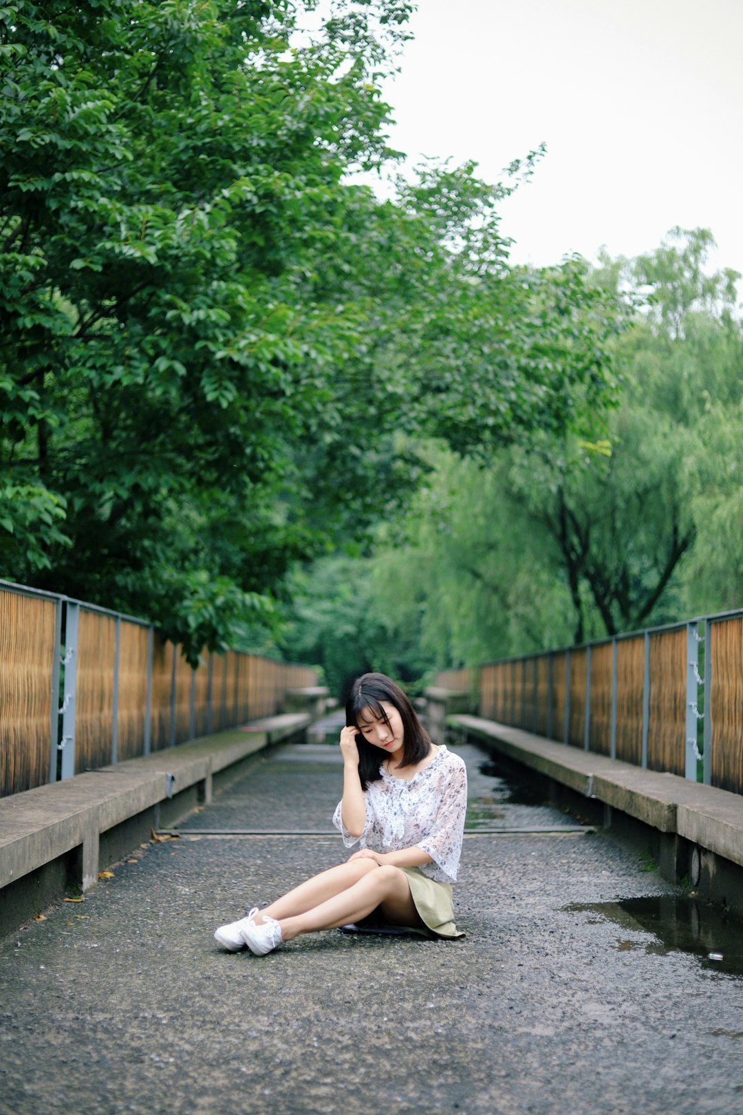 shallow focus photography of woman sitting on bridge