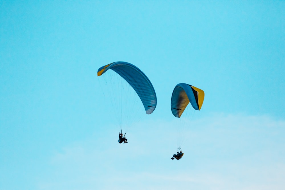 duas pessoas saltando de paraquedas durante o céu azul claro