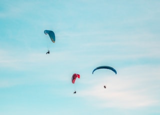 three person midair with parachutes