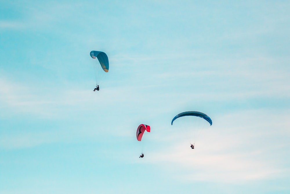 three person midair with parachutes