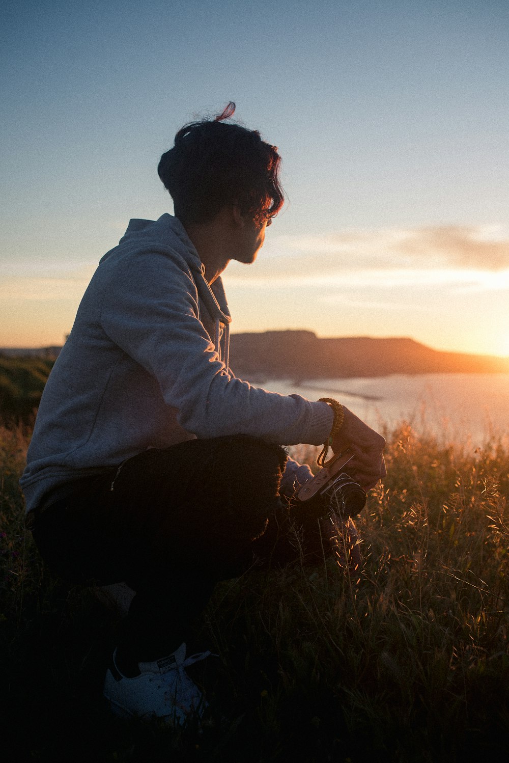 man sitting on rock while holding camera