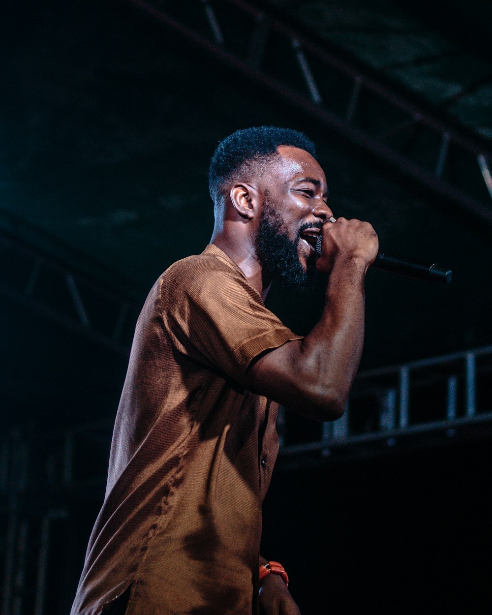 man singing on stage white wearing brown crew-neck shirt