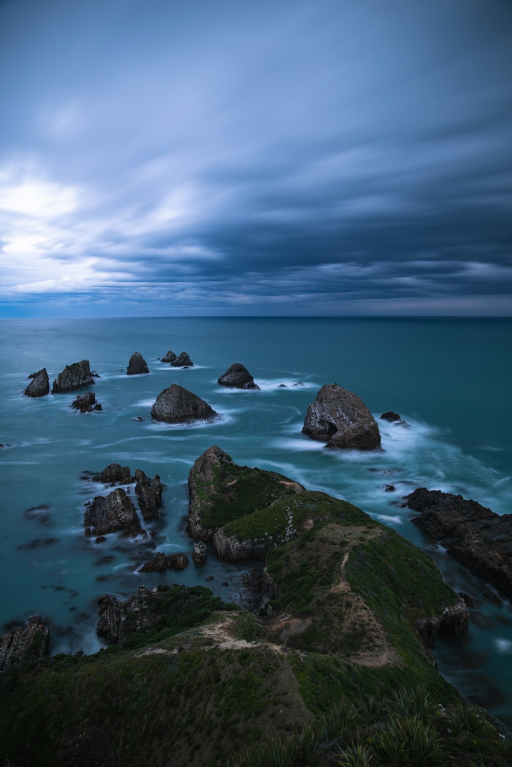 gray stones on body of water under gray clouds