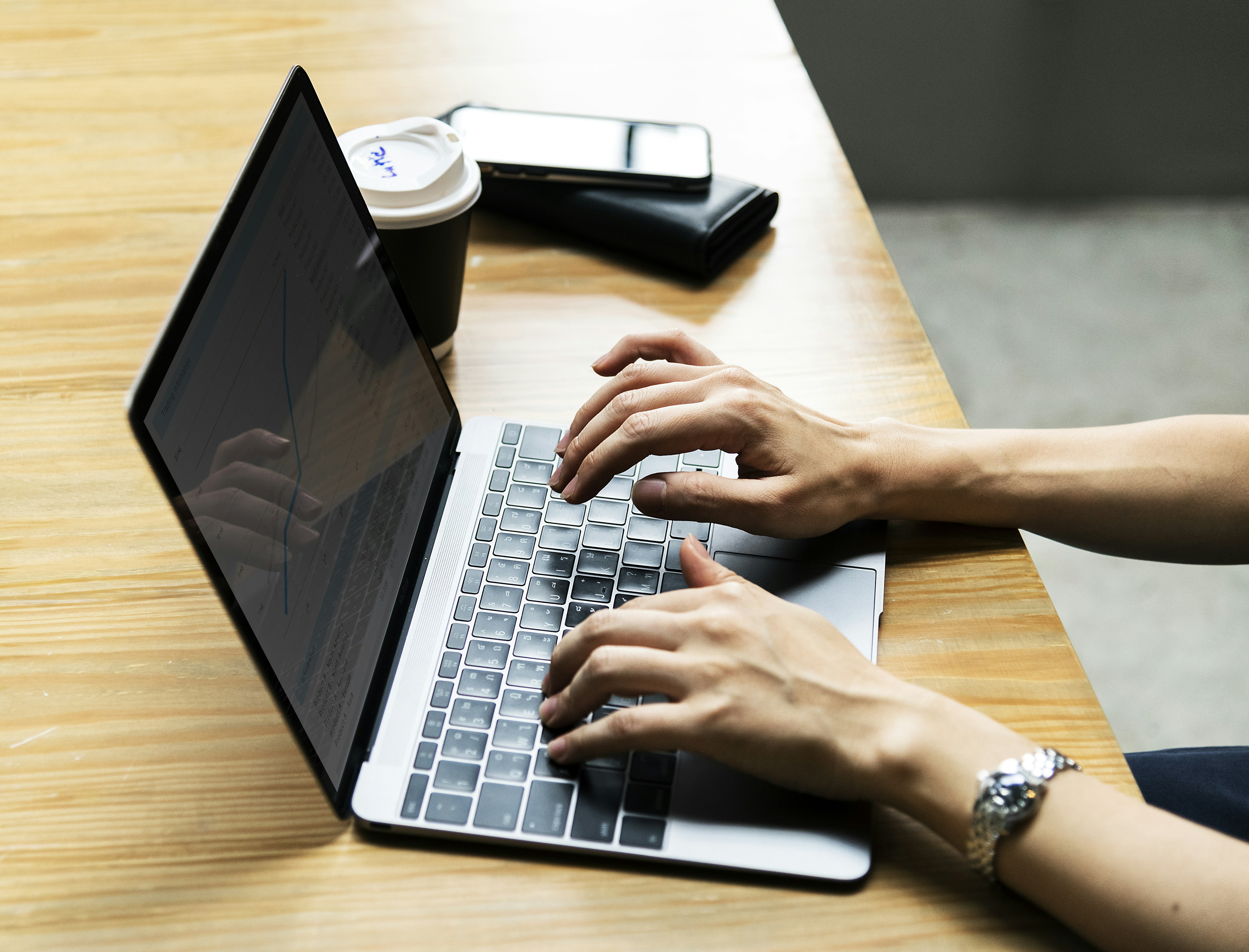 person using gray and black laptop computer on beige desk