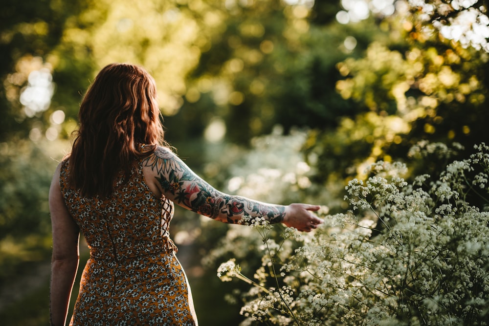 Frau, die steht, während sie weiße Blüten hält Selektive Fokusfotografie
