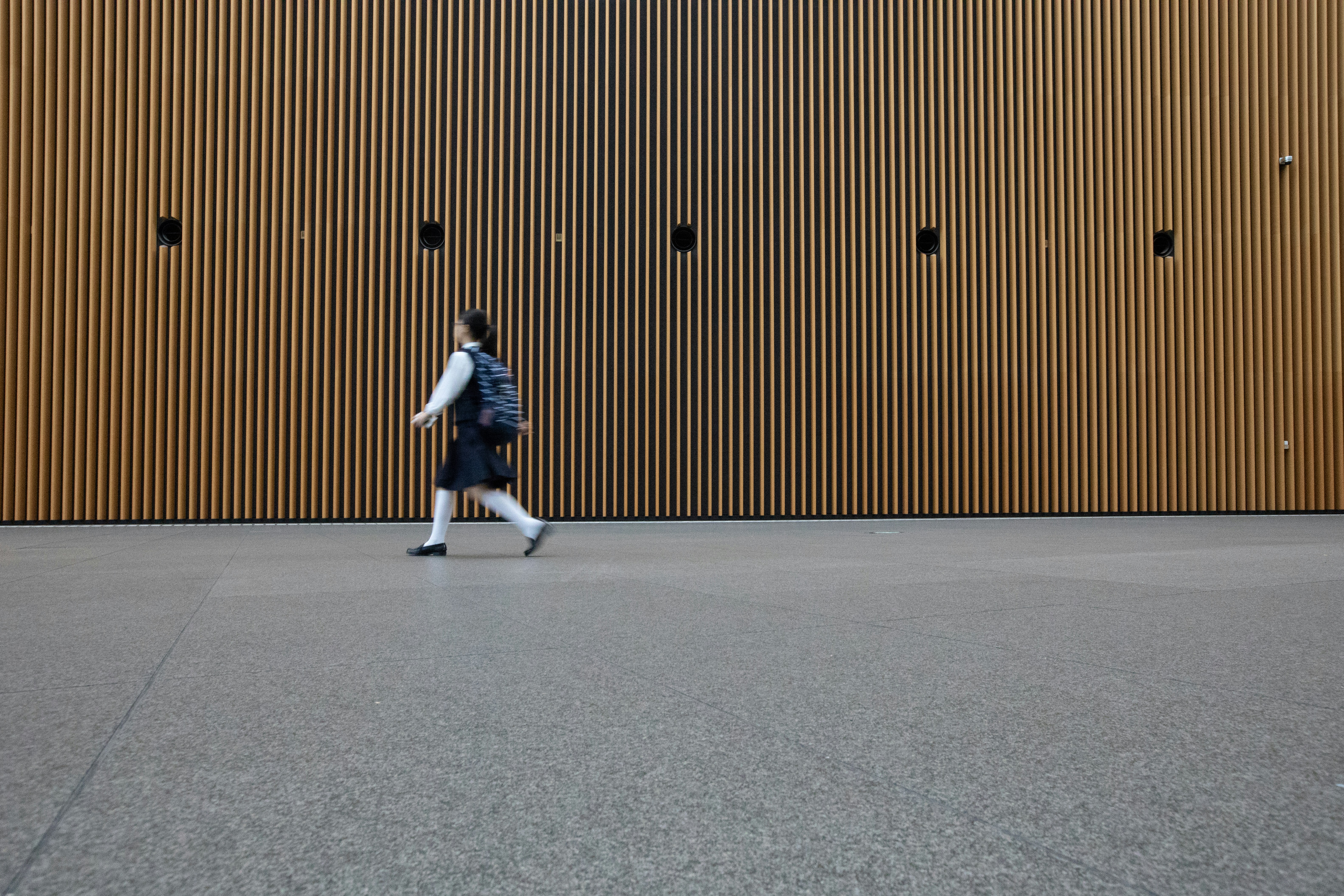 woman in uniform walkin on gray concrete pavement during daytime