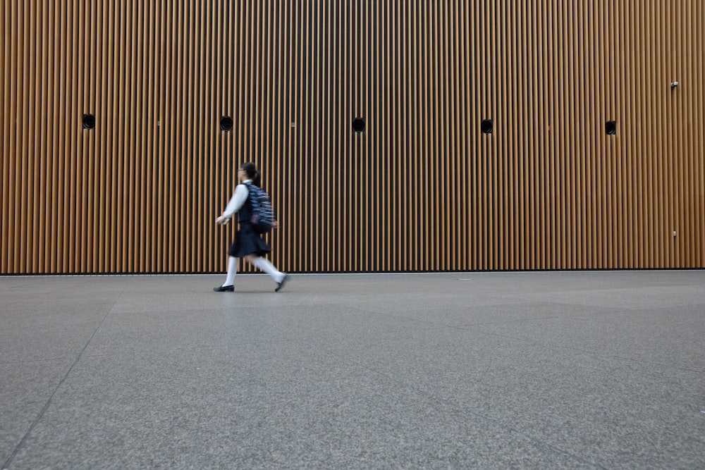 woman in uniform walkin on gray concrete pavement during daytime