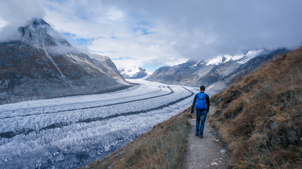 a man in a blue jacket walking down a path