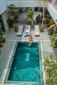 person sitting beside pool during daytime