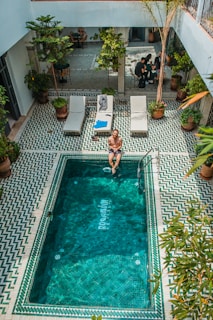 person sitting beside pool during daytime
